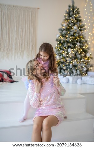 Happy family mother and child daughter near Christmas tree at home. High quality photo