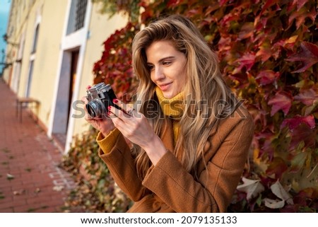 Cute woman photo enthusiast enjoying taking pictures in fall  