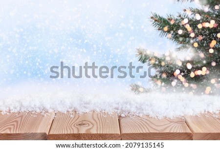 christmas background with wooden table top, snow and christmas tree