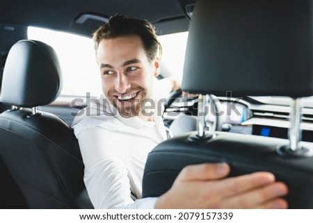Closeup portrait of a taxi driver smiling while turning over to the backseat looking talking with clients. Successful businessman husband looking at the backseat at dealer shop before buying a car Royalty-Free Stock Photo #2079157339