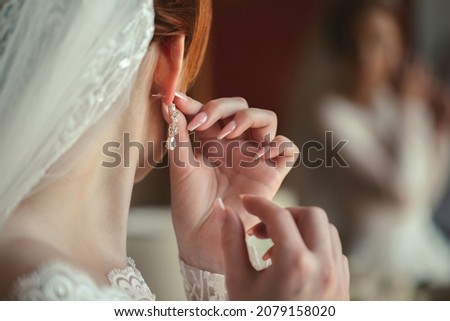 Wedding earrings on a woman's hand, she takes earrings, bride fees, morning bride, white dress, wearing earrings Royalty-Free Stock Photo #2079158020