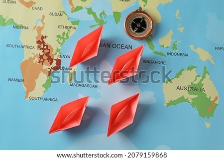 Bright paper boats and compass on world map, flat lay