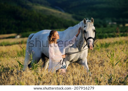 Beautiful girl with white horse in wheat field