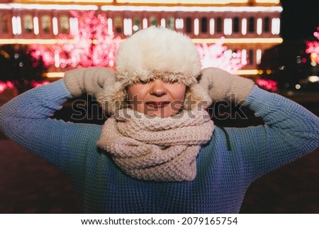 Winter night portrait of a beautiful woman in winter clothes. fur hat and mittens.