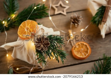 Zero waste christmas concept. Packed in natural fabric gifts and decorations from natural materials with christmas lights on a wooden table, top view