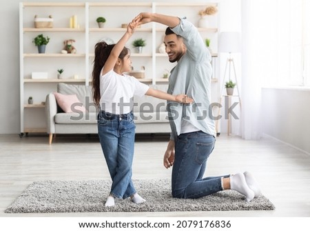 Loving arabic father dancing with his adorable little daughter at home, happy dad teaching pretty long-haired female kid dancing waltz, single father spending weekend with his child, copy space Royalty-Free Stock Photo #2079176836