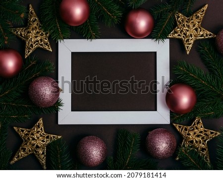 Picture frame and pink christmas baubles composition on brown background. Flat lay. Modern New year decoration photo frame.