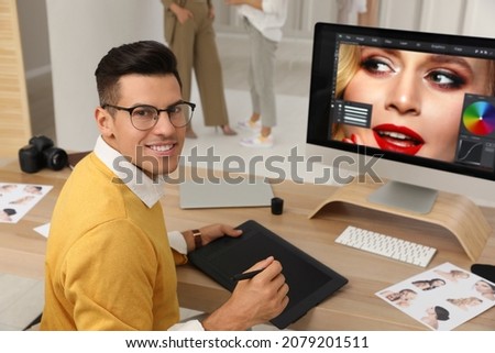 Professional retoucher working with graphic tablet at desk in photo studio