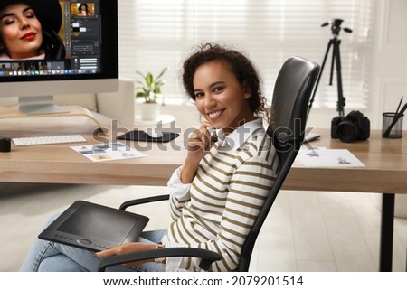 Professional African American retoucher working with graphic tablet at desk in office