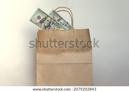 Brown paper bag with money inside, hundred dollar bills in the bag