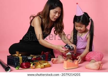 The Asian mothe teaching dauter to wrap the present box for coming celebrating season.