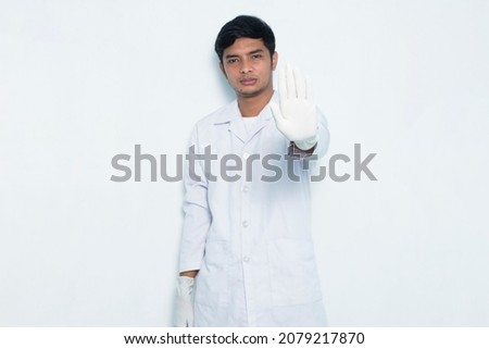 portrait of asian medical doctor open hand doing stop sign with serious expression defense gesture isolated on white background