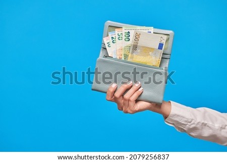 Female hands holding euro banknotes on a blue background. Euro Money or euro cash background.