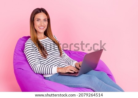 Photo of mature brown hairdo lady write laptop sit wear shirt jeans isolated on pink color background