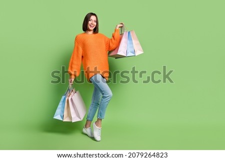 Full length body size view of attractive cheerful girl holding buyings consumerism isolated over bright green color background