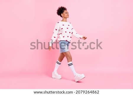 Photo of dreamy charming african lady dressed white sweater walking looking empty space smiling isolated blue color background