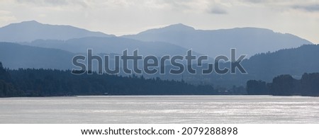 Distant mountains and lake in BC Canada. A view of a valley filled by a sea and with various layers of emerging hills and mountains with different shades of blue. Nobody, travel photo, selective focus