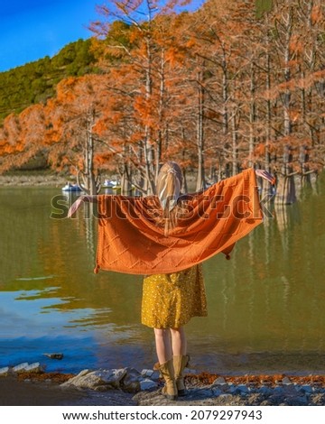 girl in a plaid and a yellow dress by the lake with swamp cypresses