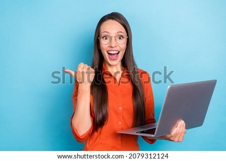 Photo of impressed funny woman wear red shirt arm spectacles holding modern device pointing empty space isolated blue color background