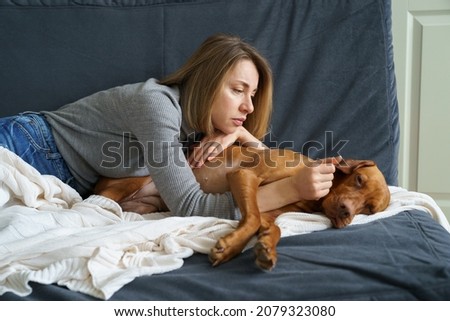 Worried woman taking care of weakening old dog at home. Poor animal suffer from stomach ache need medical treatment in vet clinic. It's time to let your friend go. Caring for aged pet at home concept Royalty-Free Stock Photo #2079323080