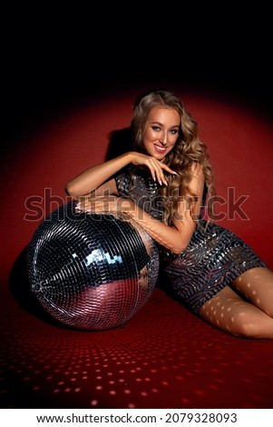 young happy blonde woman, disco ball, beautiful girl in shiny silver dress, red and black background Royalty-Free Stock Photo #2079328093