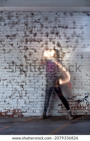 Passing time - long exposure of a dancer with light trails against a painted brick wall