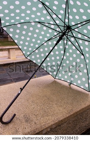 Green polka dot textile umbrella under rain into city concept