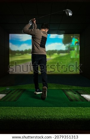 A man playing screen golf. Golf Simulator. Young golf player having playing video-game golf indoors Royalty-Free Stock Photo #2079351313