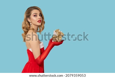 Beautiful young woman in Santa Claus dress smiles and poses with gift box. Christmas X-mas and New year celebration concept. Smiling women girl in sparkle fashion dress.