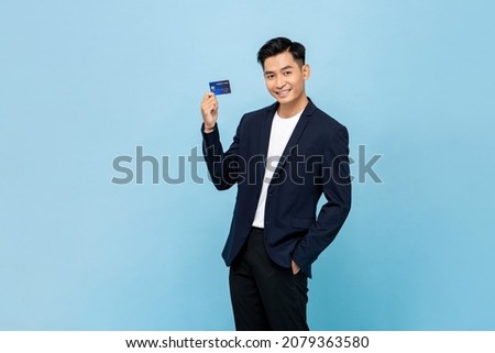 Handsome southeast Asian man in standing and showing credit card in light blue color isolated studio background Royalty-Free Stock Photo #2079363580