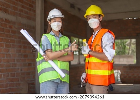 engineer concept The two engineers holding paper plan, hammer and other devices and standing for taking a picture of working atmosphere.