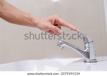 The faucet in the bathroom with running water. Man turning off the water to save water energy and protect the environment. world environment day Royalty-Free Stock Photo #2079395134