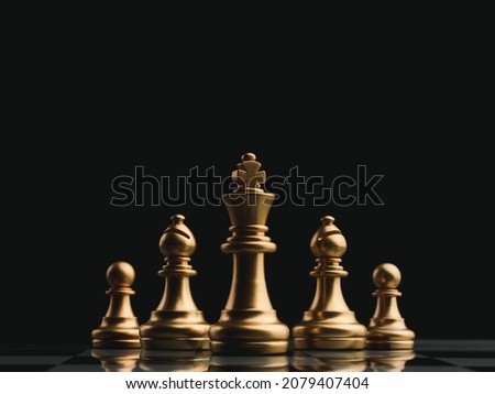 The set of golden chess pieces leading by king follwing with knight and pawn standing on chessboard on dark background. Leadership, teamwork, partnership, planning, and business strategy concept.