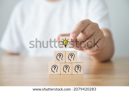 Concept creative idea and innovation. Hand picked wooden cube block with light bulb icon on top pyramid and head human symbol Royalty-Free Stock Photo #2079420283