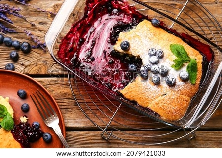 Baking dish with blueberry cobbler on wooden background