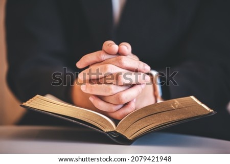 focus on woman's hand While praying for Christianity with blurry body background, praying with her hands with scriptures.