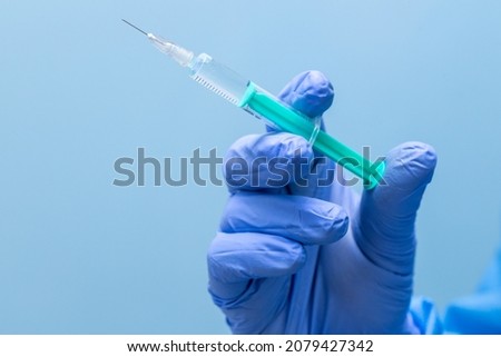 Ready-to-use syringe held in hands, Rubber blue disposable gloves, medical, Syringes prepared in the background