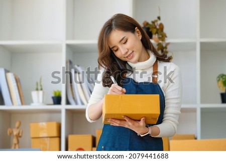 Work from home. happy women selling products online Start a small business owner by using smartphone and laptop computer to calculate prices and prepare for postage.