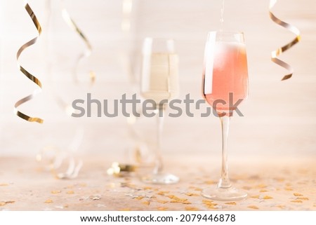 New Year's glasses with pink and white champagne on a white background with glitter and tinsel. Front view.