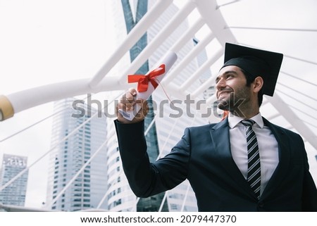 Handsome businessman wear graduation degree hat and stand on stair near cityscape, business education concept Royalty-Free Stock Photo #2079447370