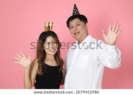 The Asian couple standing on the pink background.