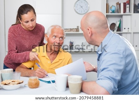 Adult children help an older father sign documents. High quality photo