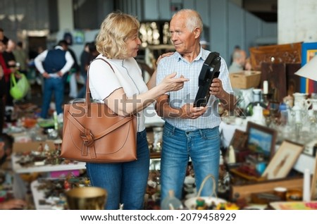 Mature man and his wife are visiting market of old things. High quality photo
