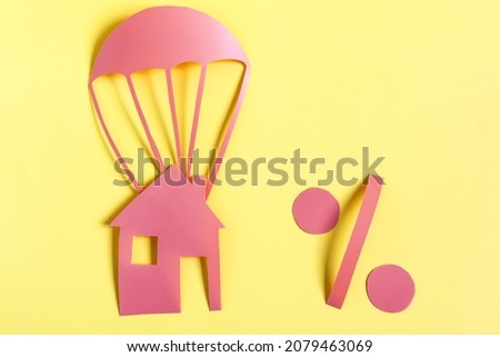 Minimalistic picture of a parachute and a percent sign made of red cardboard on a yellow background