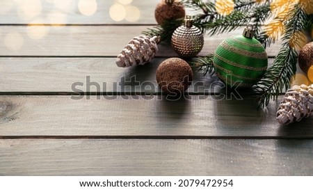 Christmas holiday background with bulbs, fir tree branches and ornaments on wooden background with Christmas lights bokeh, Merry Christmas greeting card with copy space