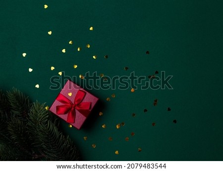 Red gift box with bow and sequins on a green background view from above. Christmas gift flat lei