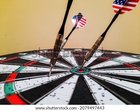Photo of three darts that hit the dart board and one hitting the bulls eye