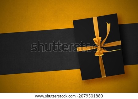 Black gift box with a golden ribbon with a colorful background. Black Friday concept