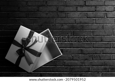 Opened a white gift box with a black ribbon with a black wall background. Black Friday concept