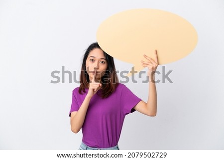 Young Vietnamese woman isolated on white background holding an empty speech bubble and doing silence gesture